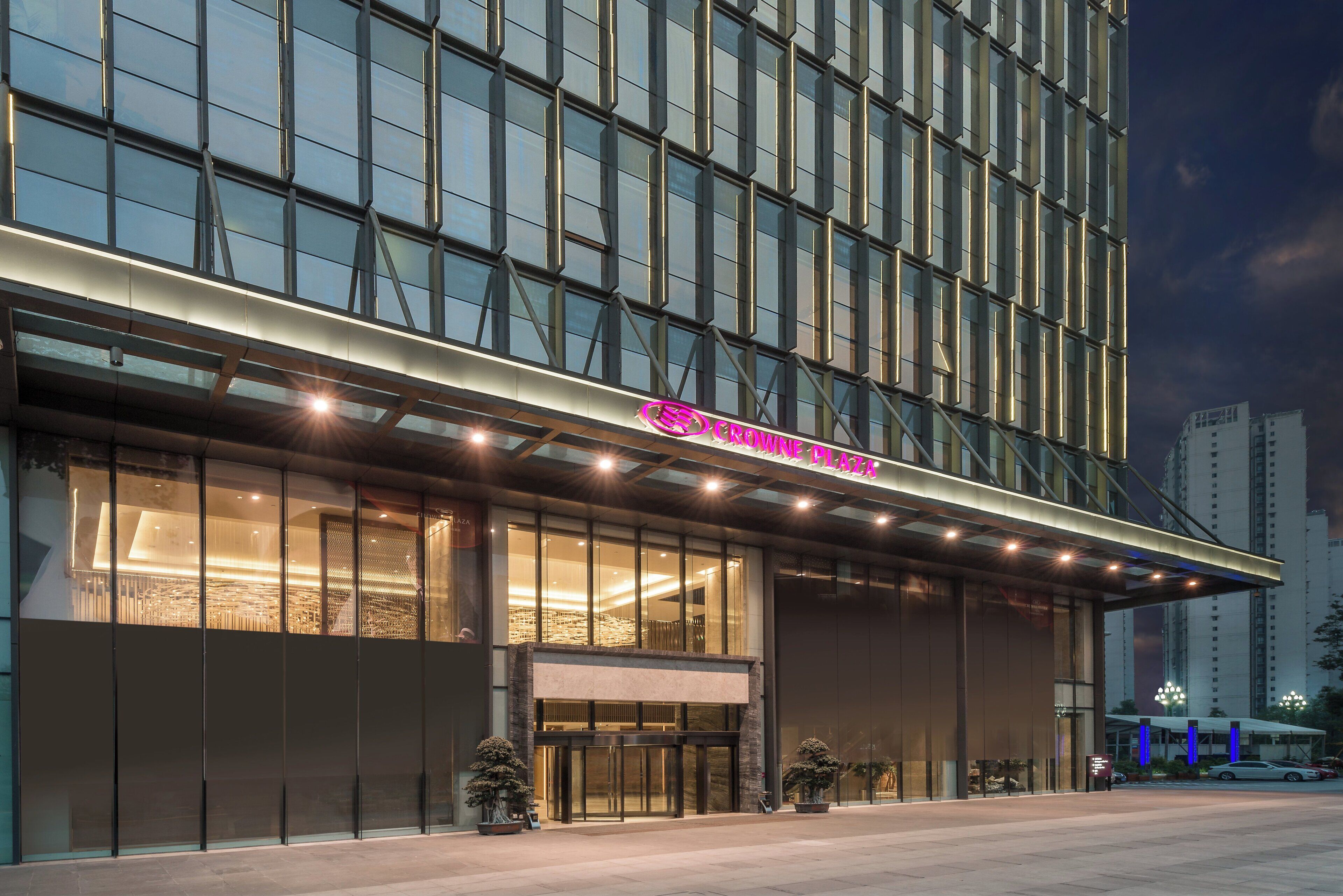 A modern hotel with a glass facade, a prominent entrance, and a sign reading 'Crown Plaza'.