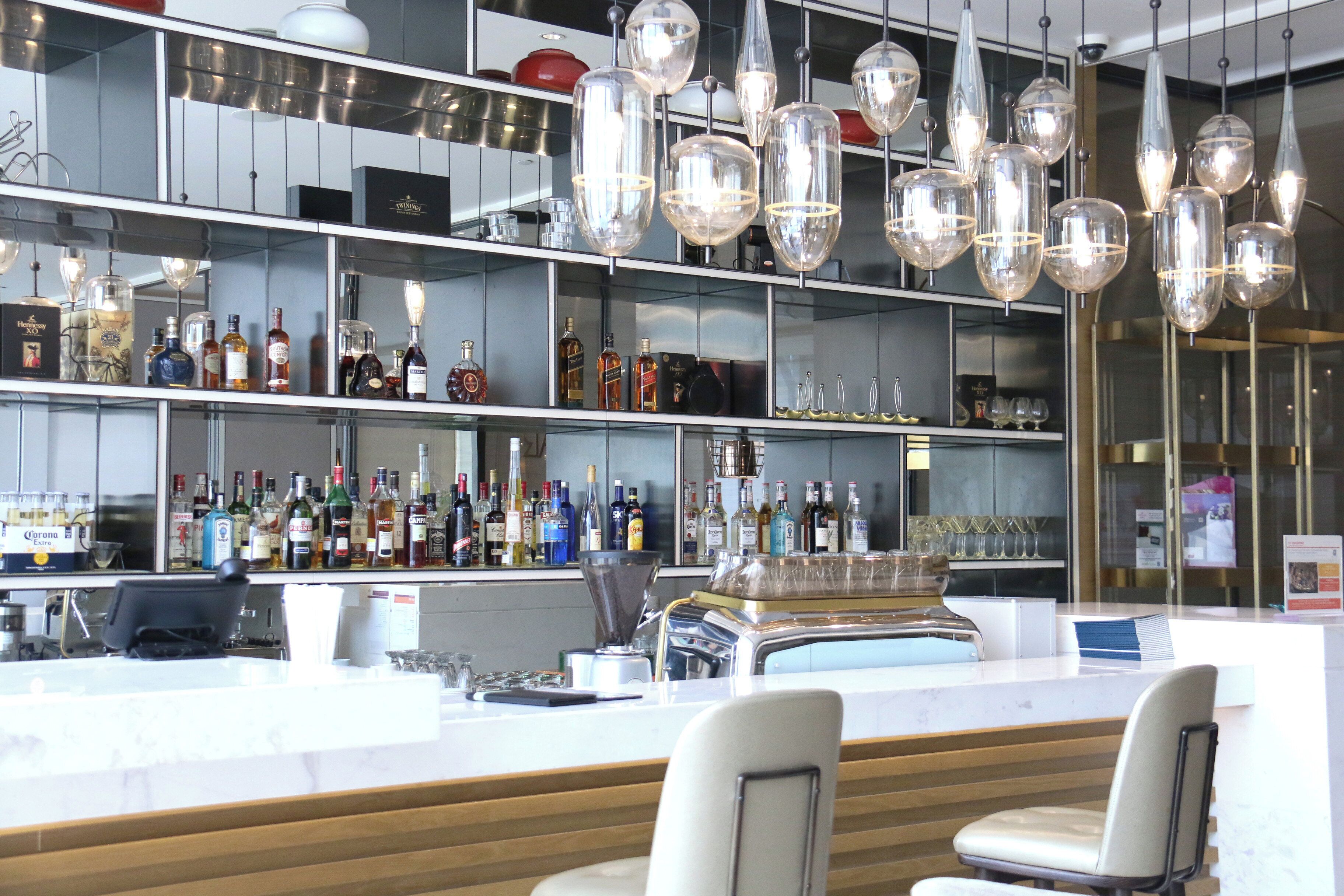 Un espace bar doté de plusieurs étagères remplies de bouteilles d’alcool, d’un comptoir et de luminaires suspendus.