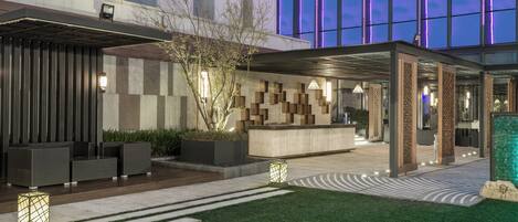 A modern hotel lobby with a reception desk, seating area, and a glass facade.