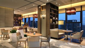 A modern hotel lobby with seating areas, a coffee table, and a bookshelf.