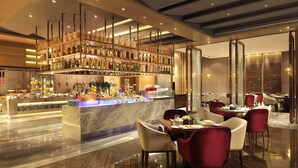 En modern restaurang med en bardisk i marmor, röda stoppade stolar och ett brett utbud av mat- och dryckesalternativ.