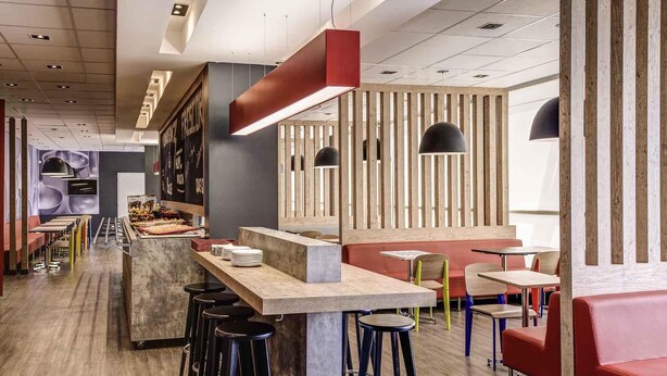 Un interior de restaurante moderno con barra, taburetes altos y una variedad de opciones de asientos.
