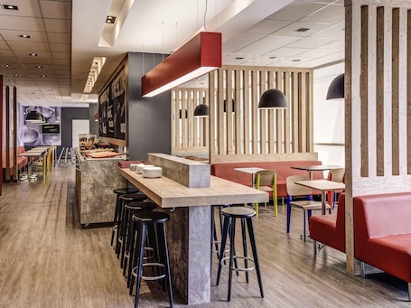 A modern restaurant interior with a bar area, high stools, and a mix of seating options.