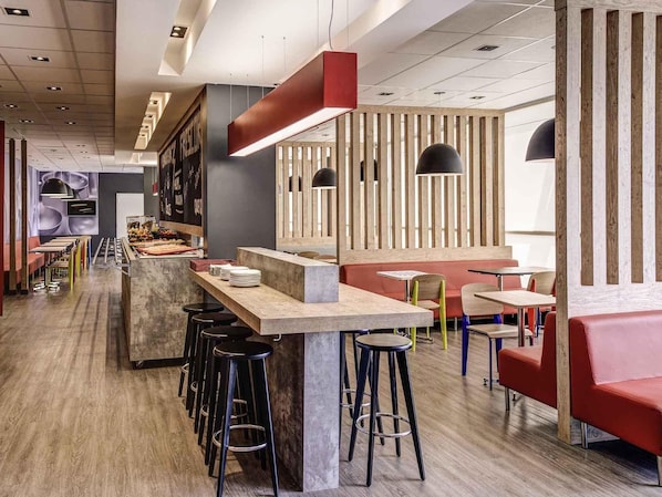 Ein modernes Restaurantambiente mit Barbereich, hohen Barhocker und verschiedenen Sitzmöglichkeiten.