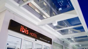 Exterior del hotel ibis con fachada de vidrio moderna y un cartel que indica que se encuentra en Recife Aeroporto.
