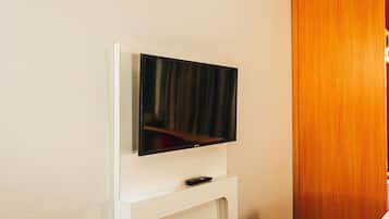 A television mounted on a white stand in a room with a wooden door.
