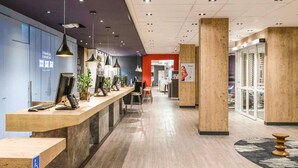 Zona de recepción con mostrador de madera, múltiples monitores de ordenador y señal de accesibilidad para sillas de ruedas.