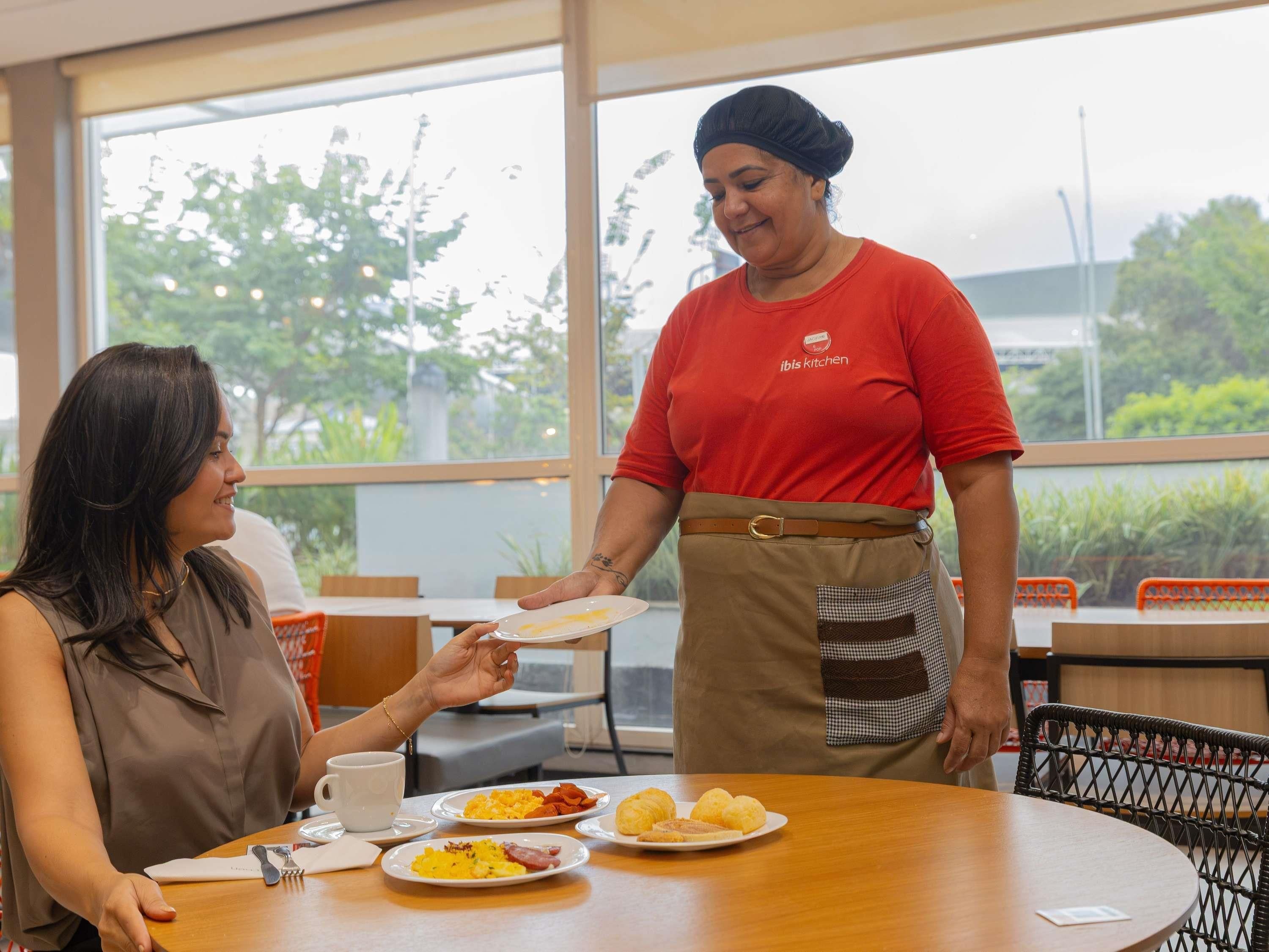 A restaurant setting with a waitress serving food to a customer.