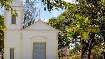 A small church with a white facade, a cross on top, and a door with a window on the left side.