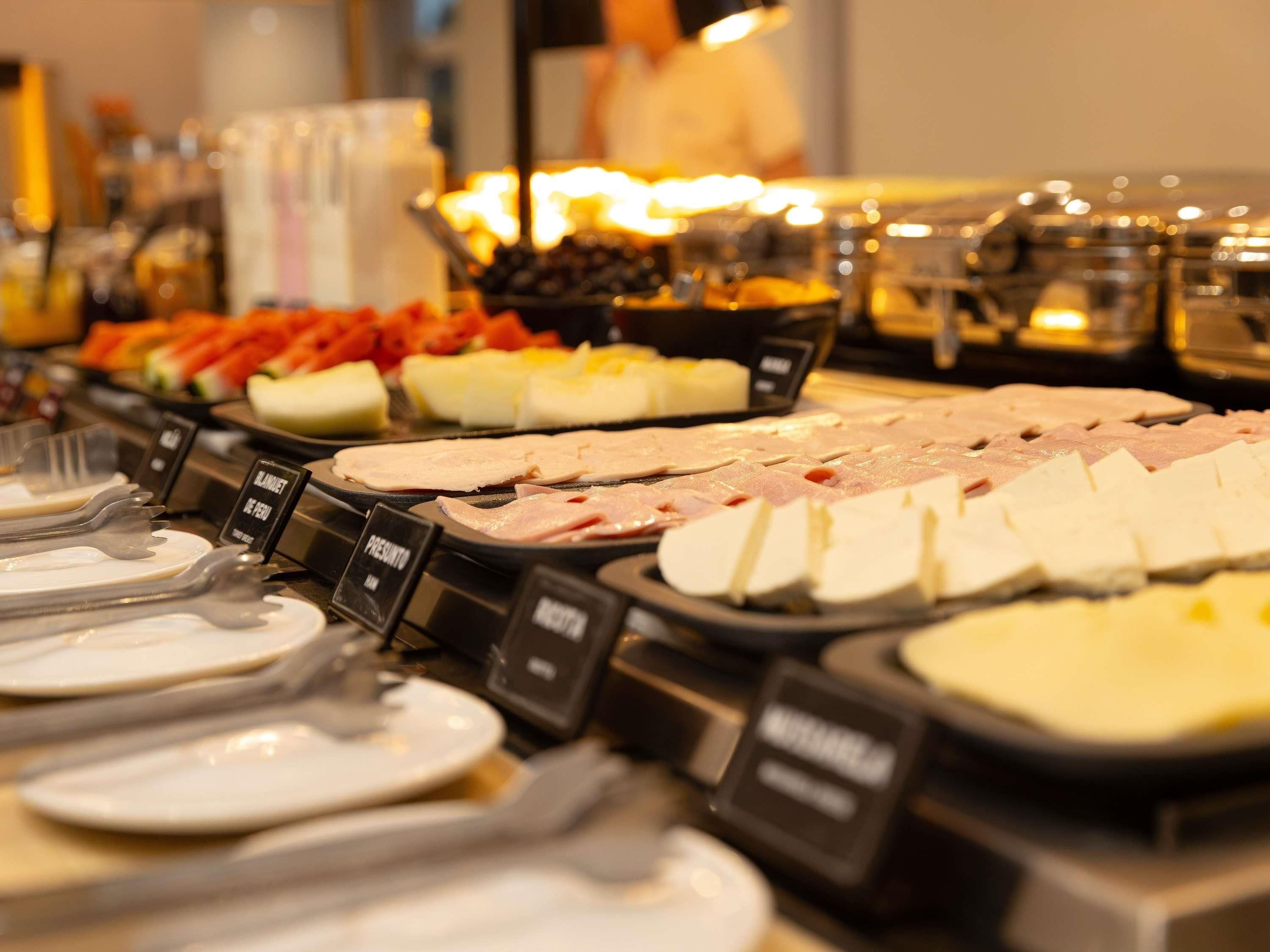Buffet com diversas opções de carne e uma pessoa ao fundo.
