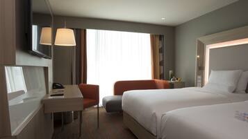 A hotel room with a bed, a desk, a chair, and a TV.