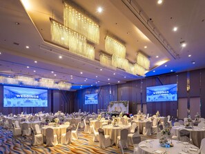 A large banquet hall with round tables, white chairs, and floral centerpieces. - Novotel Manila Araneta City Hotel (Quezon City)