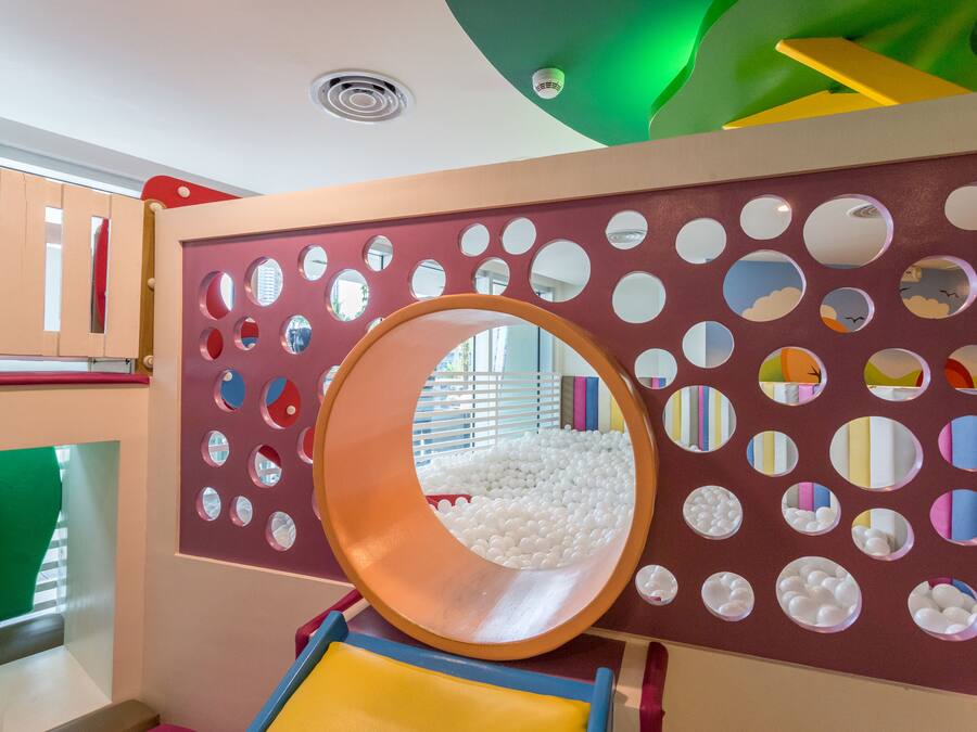A play area with a slide, colorful walls, and a ball pit.