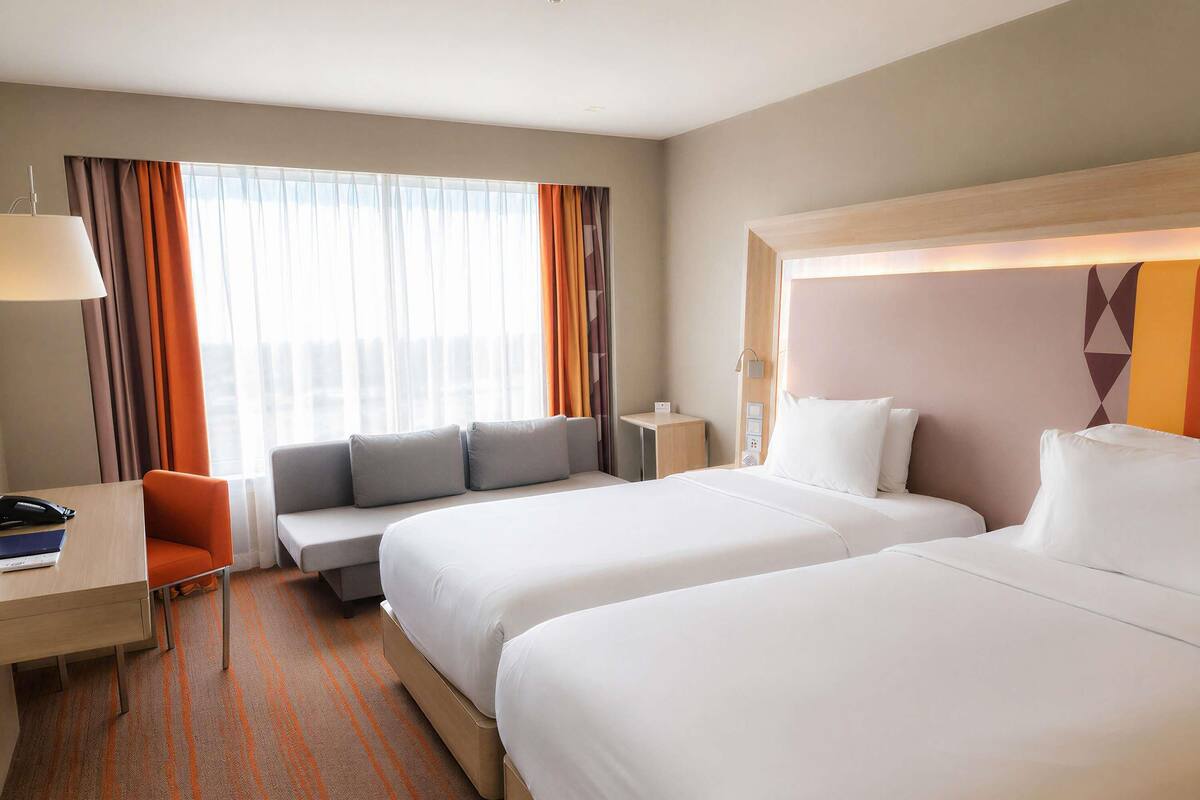 Une chambre d’hôtel avec deux lits, un bureau, une chaise et un canapé.