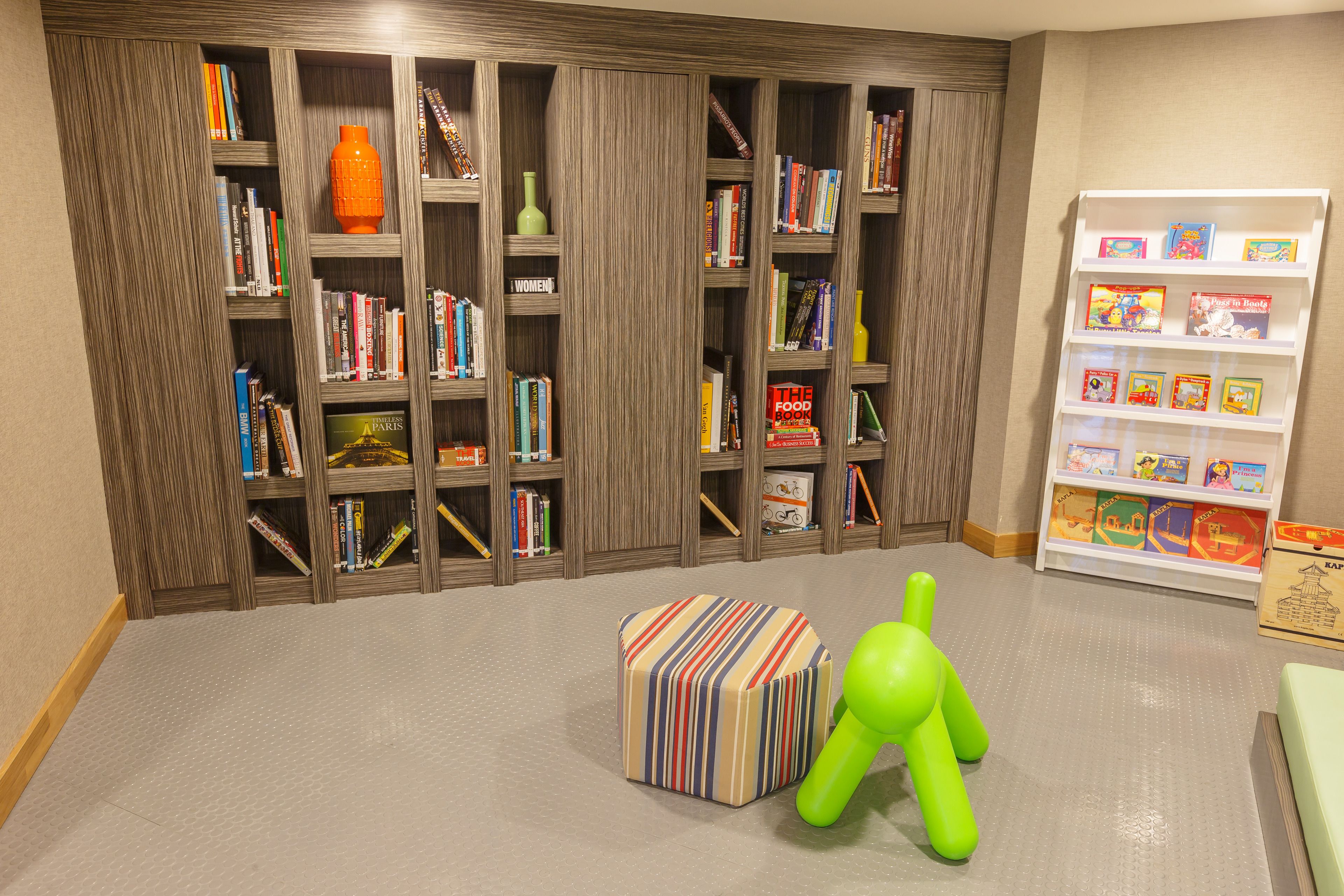 A library with wooden bookshelves filled with books and a small white shelf with children's books.