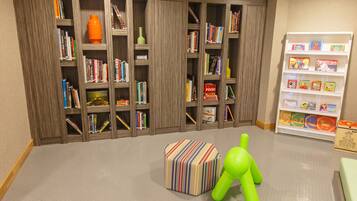 A library with wooden bookshelves filled with books and a small white shelf with children's books.