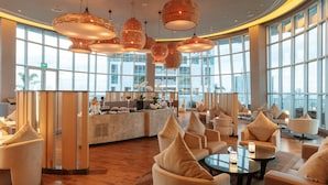 A spacious lobby with a reception desk, comfortable seating, and large windows offering a city view. - Novotel Manila Araneta City Hotel (Quezon City)