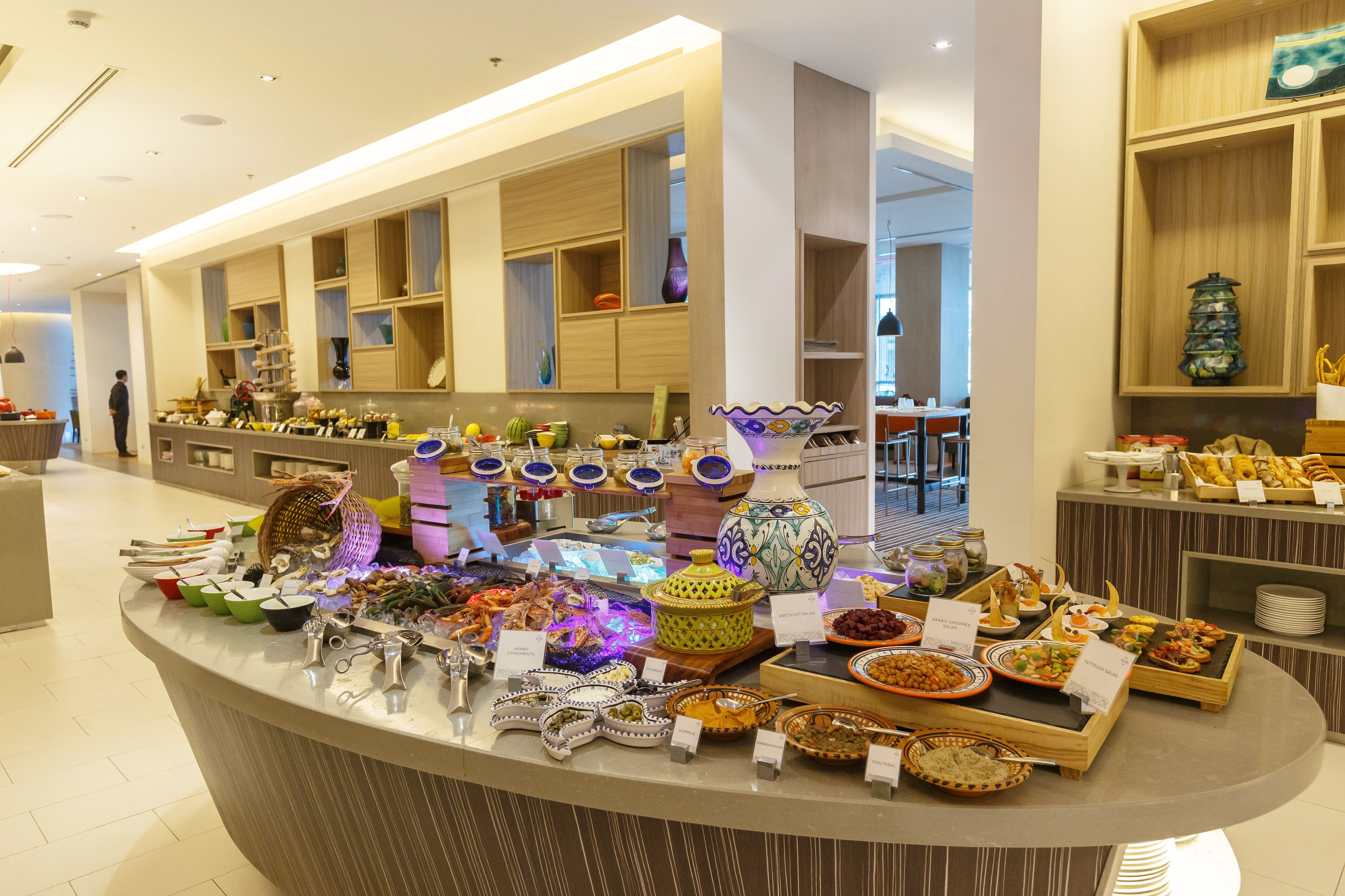A buffet with various dishes and a person standing in the background.