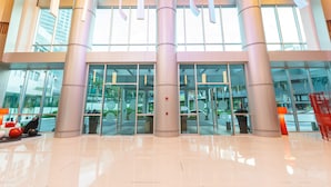 A modern building entrance with large glass doors, reflective floors, and tall columns. - Novotel Manila Araneta City Hotel (Quezon City)