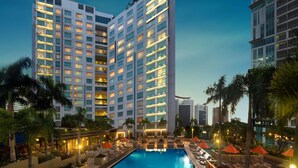 A Novotel hotel with a pool area, palm trees, and modern architecture. - Novotel Manila Araneta City Hotel (Quezon City)