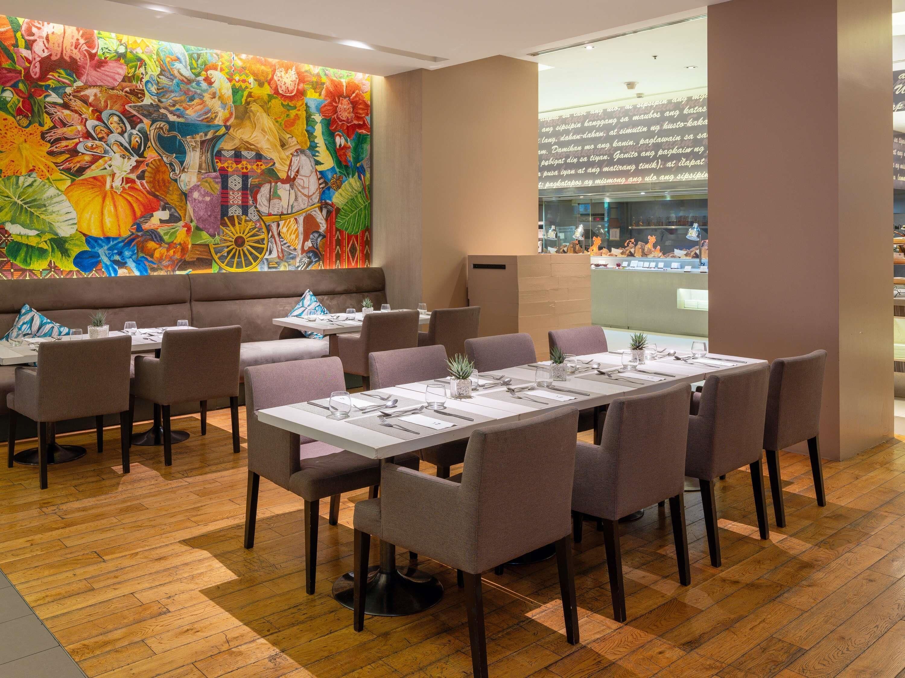 A restaurant with a large mural, wooden flooring, and a variety of seating options including booths and tables.