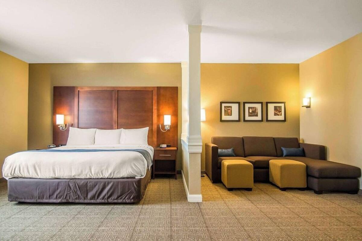 Una habitación de hotel con una cama grande, un sofá y una mesita.