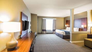 A hotel room with a bed, a desk with a lamp, a chair, and a television.