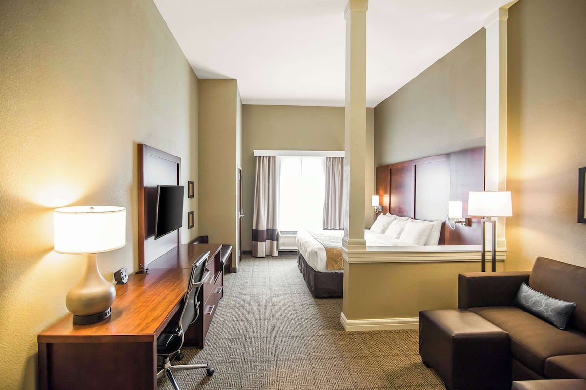 Habitación de hotel con escritorio, silla, sofá, cama y televisor.