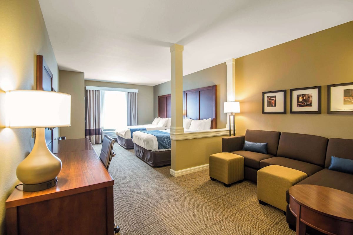 Habitación de hotel con dos camas, un sofá, un escritorio y una lámpara.