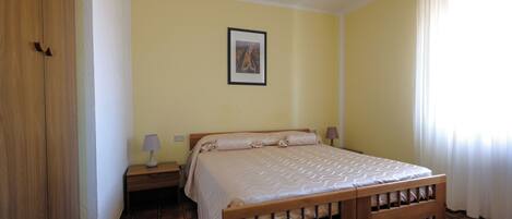 A bedroom with a wooden bed, a nightstand, a lamp, and a framed picture on the wall.