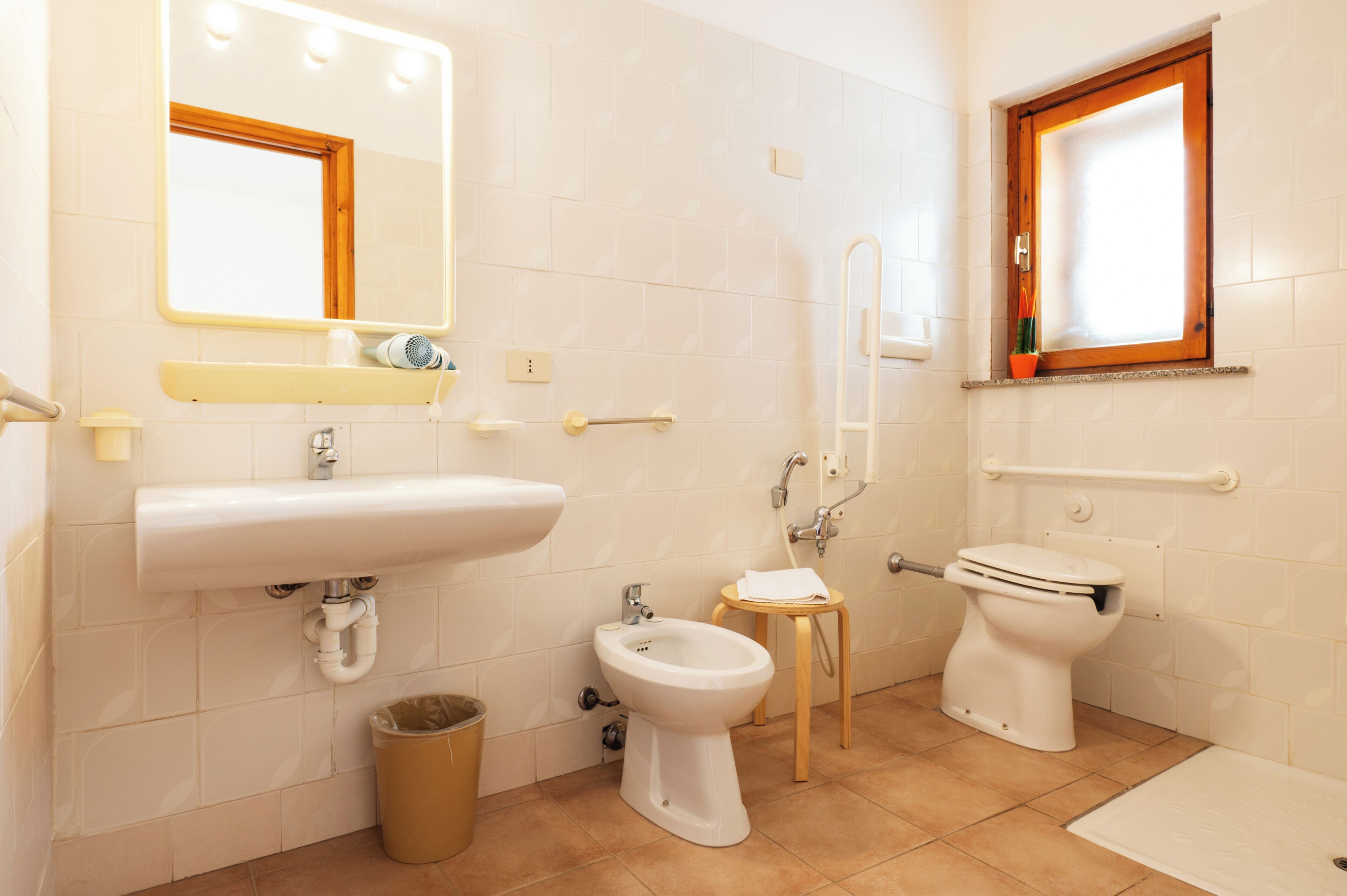 Un baño con lavamanos, bidé, inodoro y un taburete pequeño.