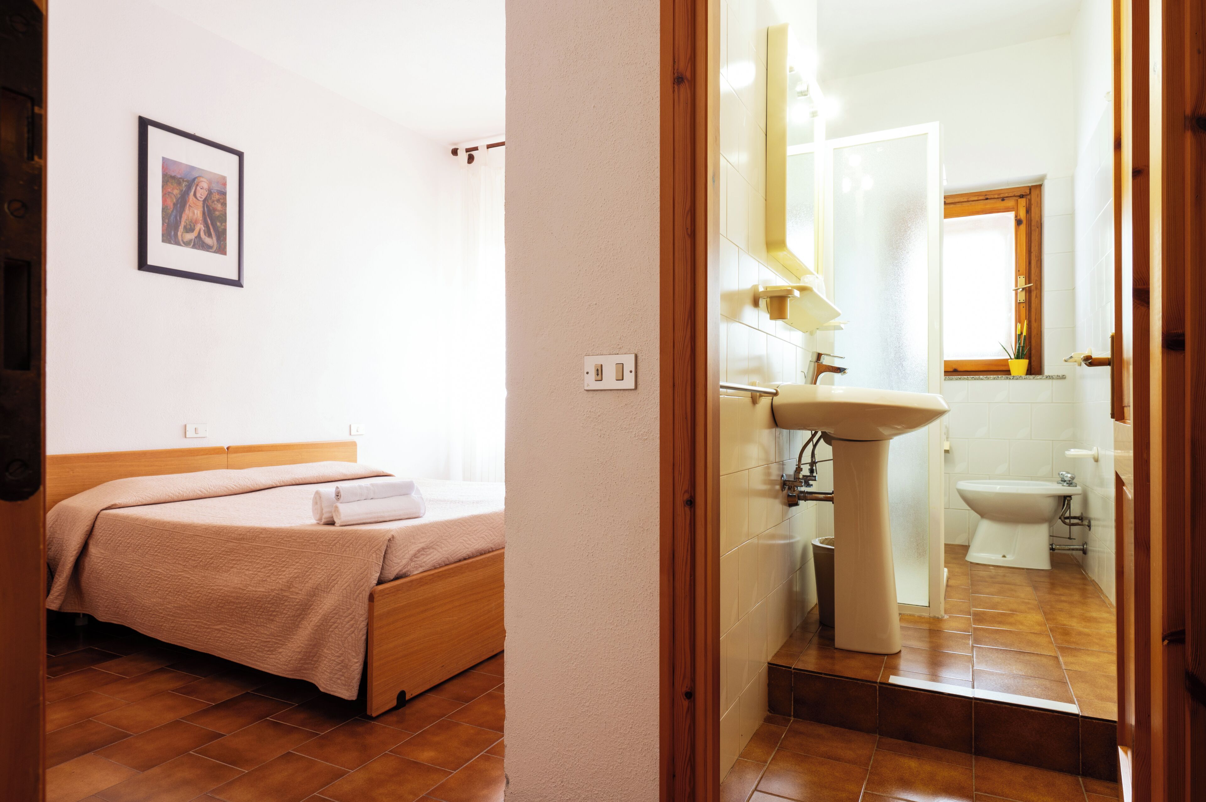 A bedroom with a bed, a bedside table, and a wall-mounted picture.