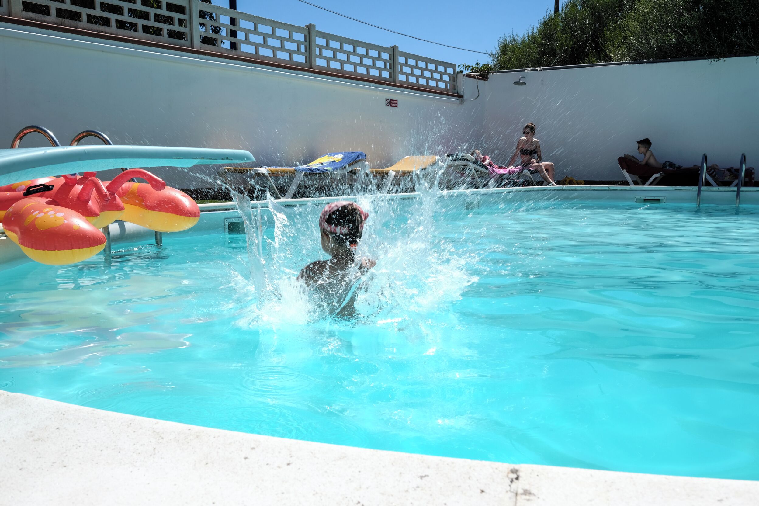 A swimming pool with inflatable toys and a person in the water.