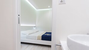 Een moderne hotelkamer met een bed, een wit ligbad en een licht houten vloer.