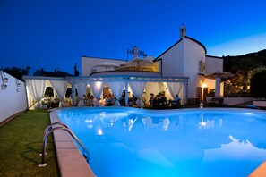 A poolside area with a clear view of the pool, a covered seating area, and a building with a 'HOTEL' sign.