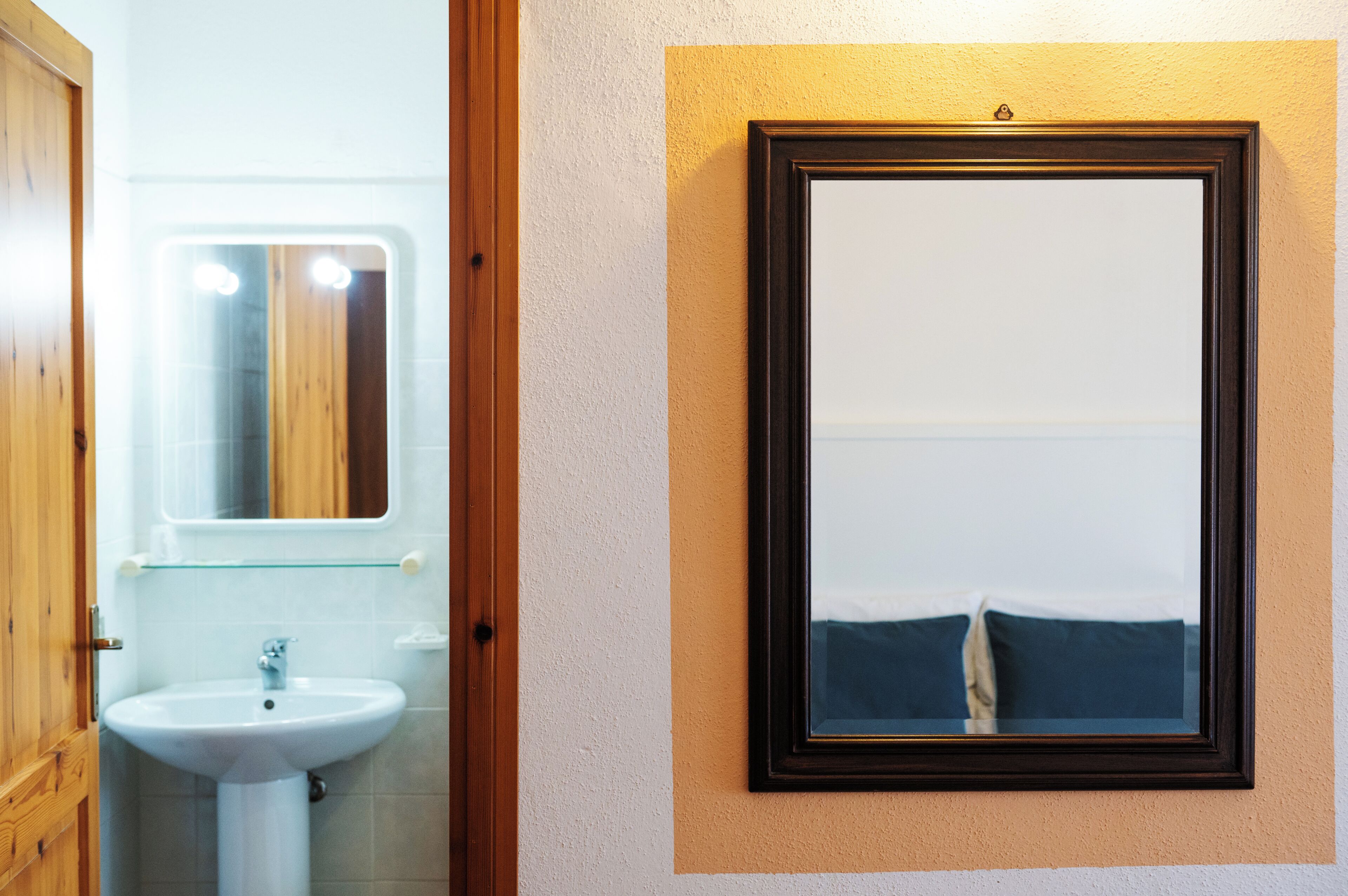 A bathroom with a white sink, a mirror, and a framed picture on the wall.