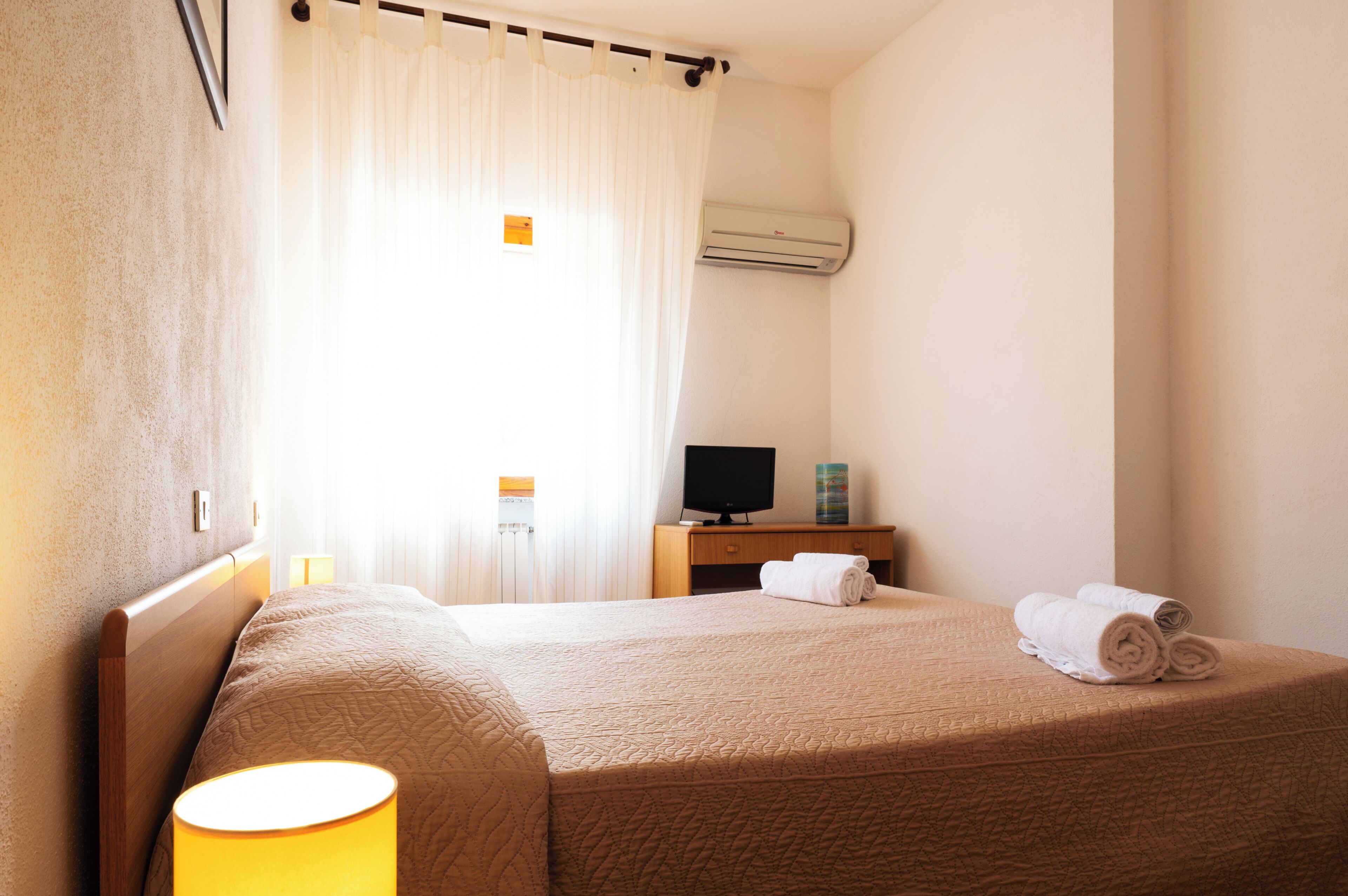 Een hotelkamer met een bed, een televisie, een bureau en een lamp.