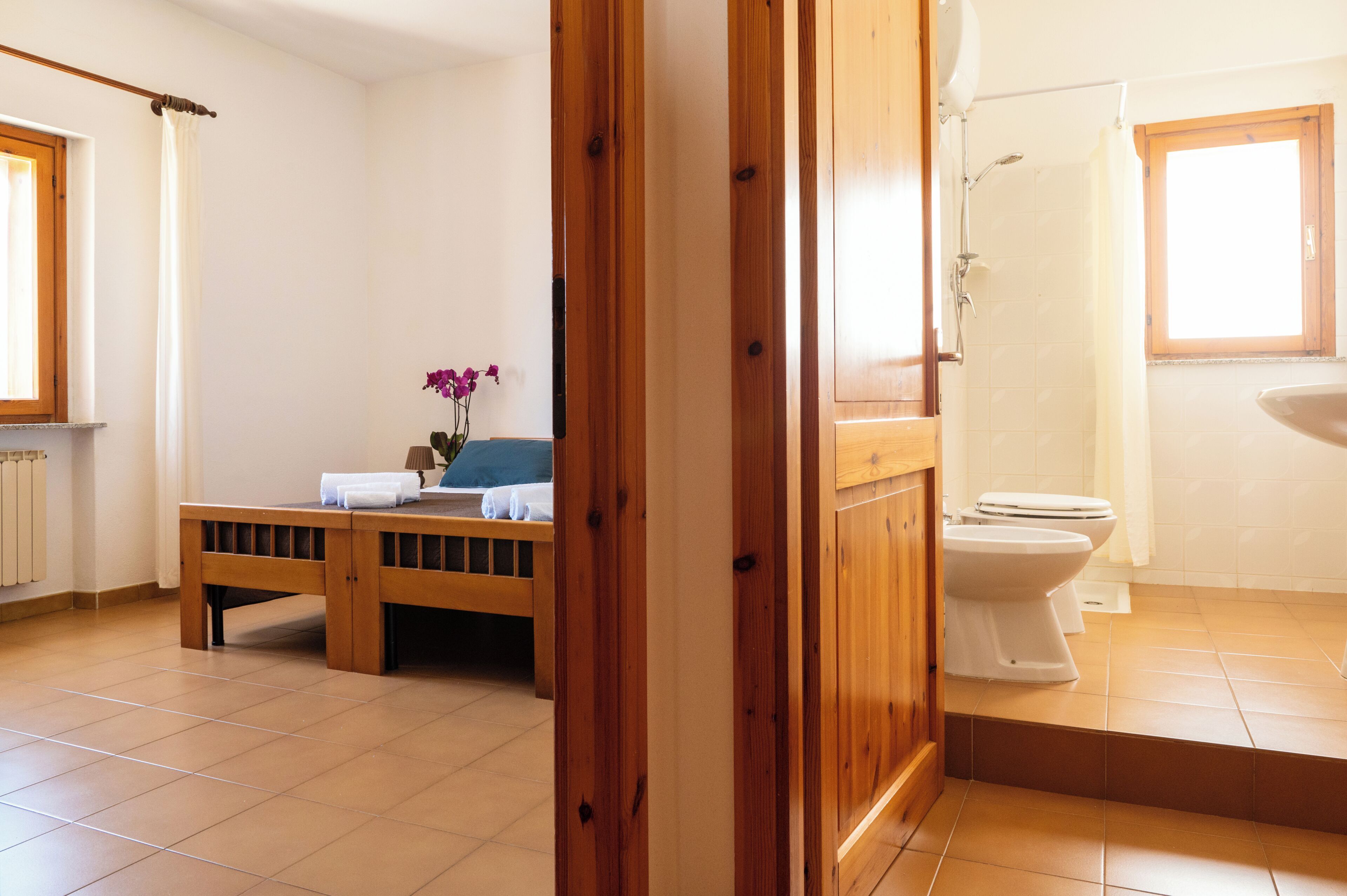 A bathroom with a toilet, shower, and a window.