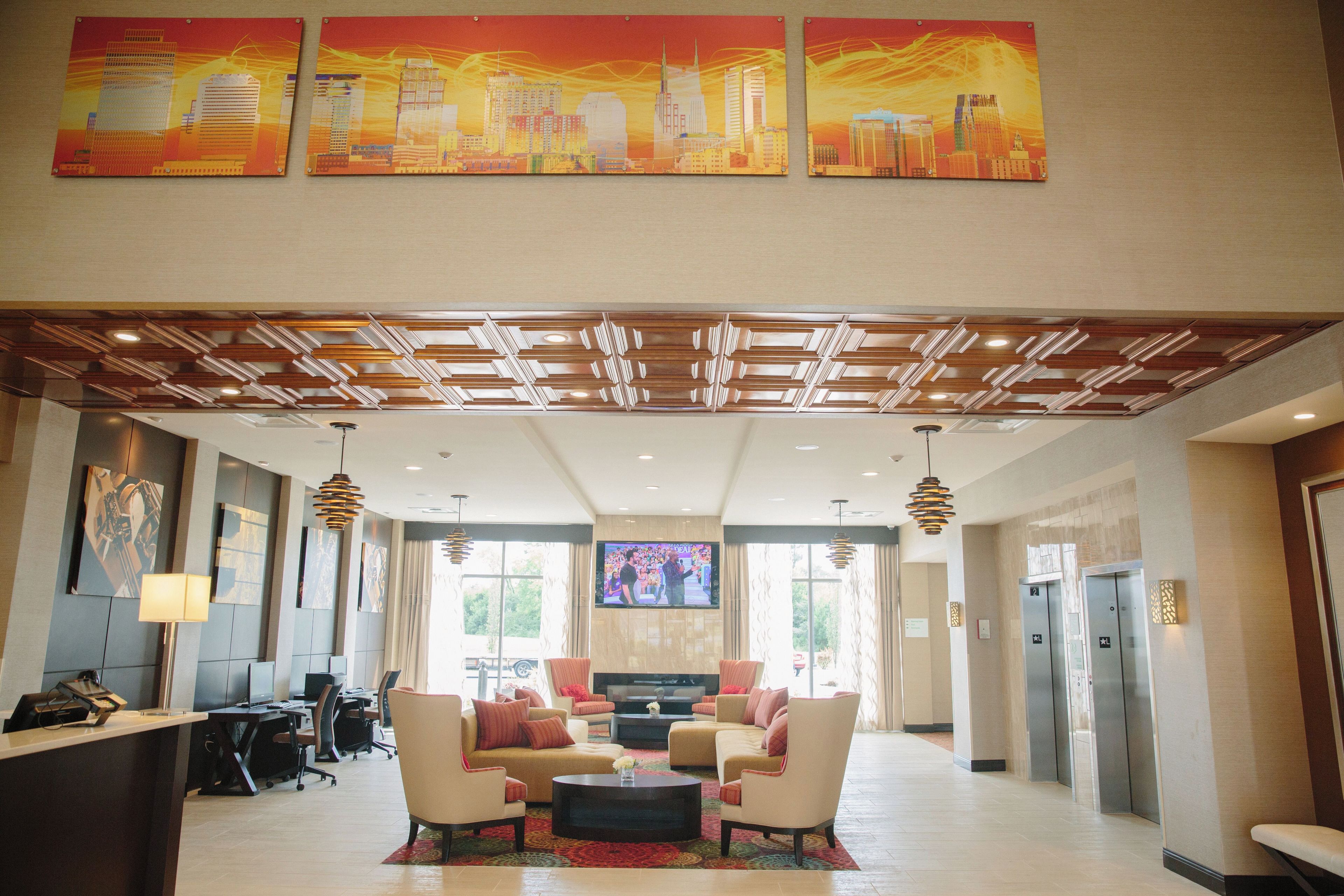 A hotel lobby with a reception desk, seating area, and artwork on the walls.