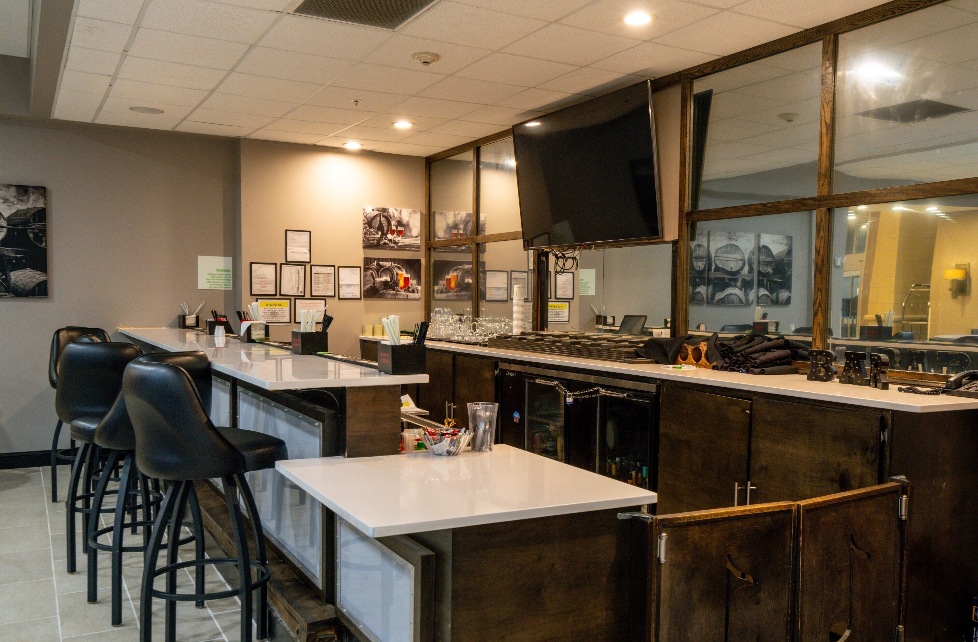 Un área de bar con taburetes, una barra y un televisor montado en la pared.