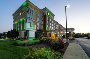Un hotel Holiday Inn con un jardín bien cuidado y una entrada cubierta.