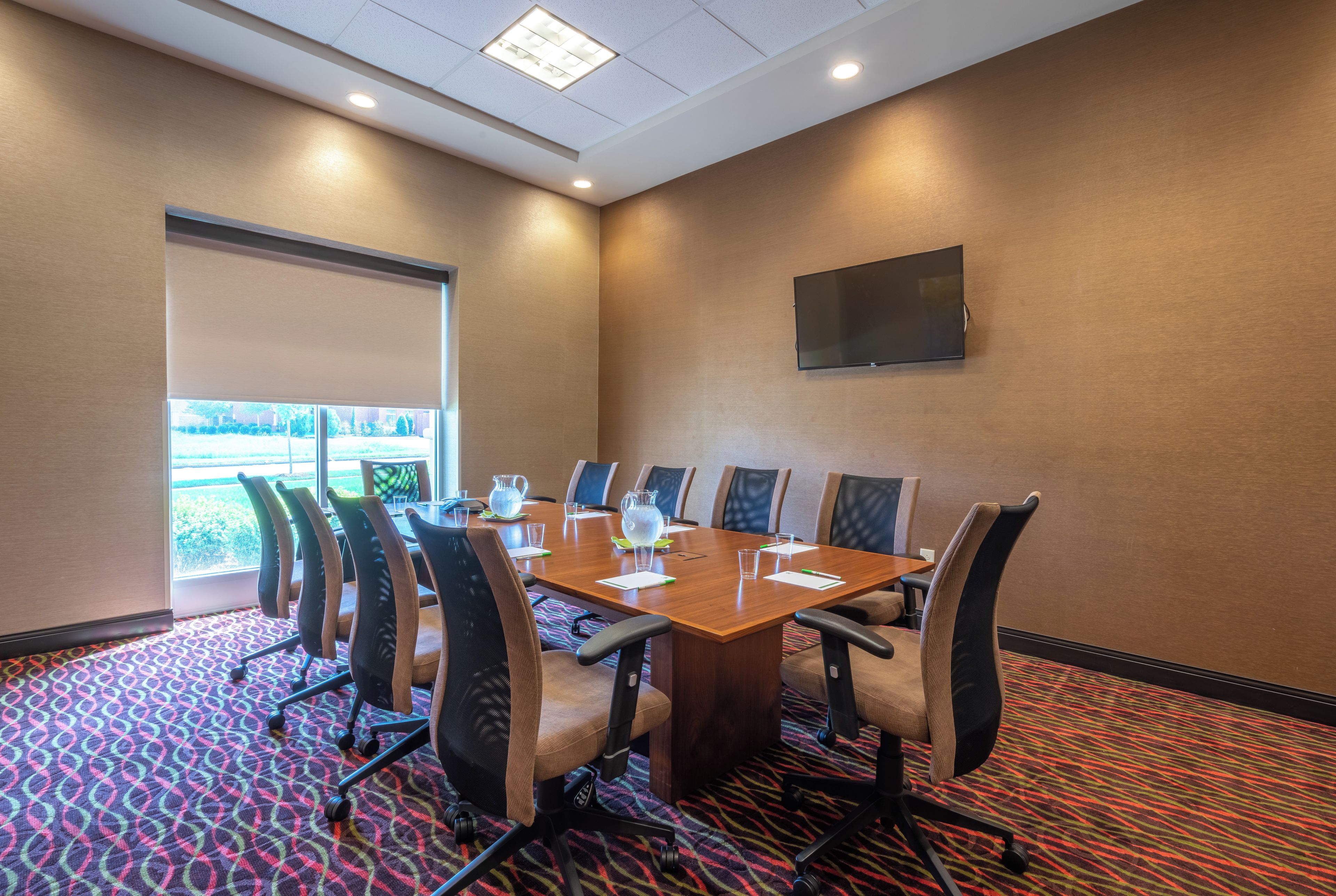 A conference room with a large table, chairs, and a television on the wall.