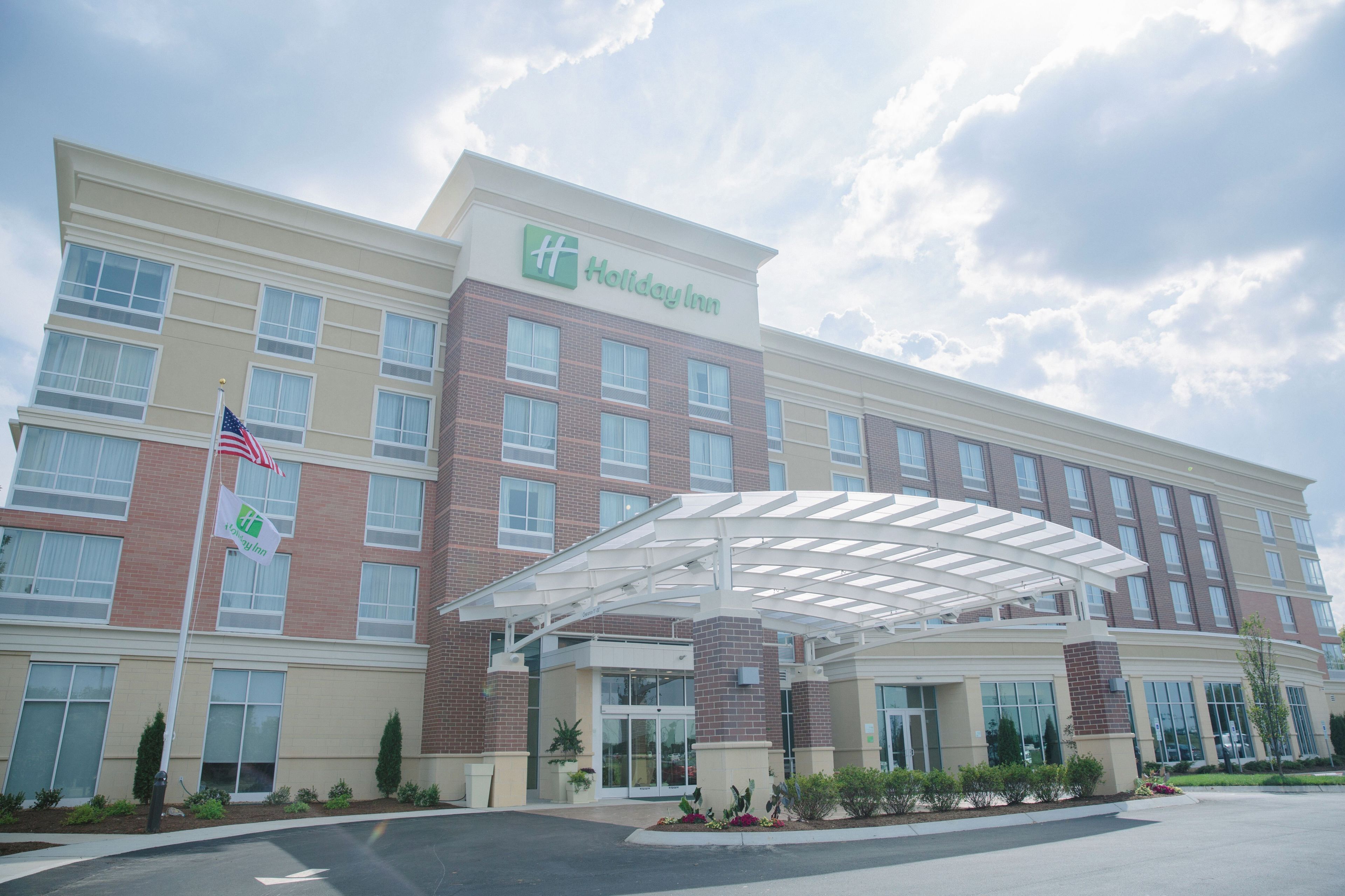 Ein Holiday Inn Hotel mit überdachter Eingangspartei, Ziegelhausfassade und einer Flagge.