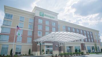 Ein Holiday Inn Hotel mit überdachter Eingangspartei, Ziegelhausfassade und einer Flagge.