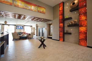 A spacious lobby with a modern design, featuring a seating area, a reception desk, and a television screen.