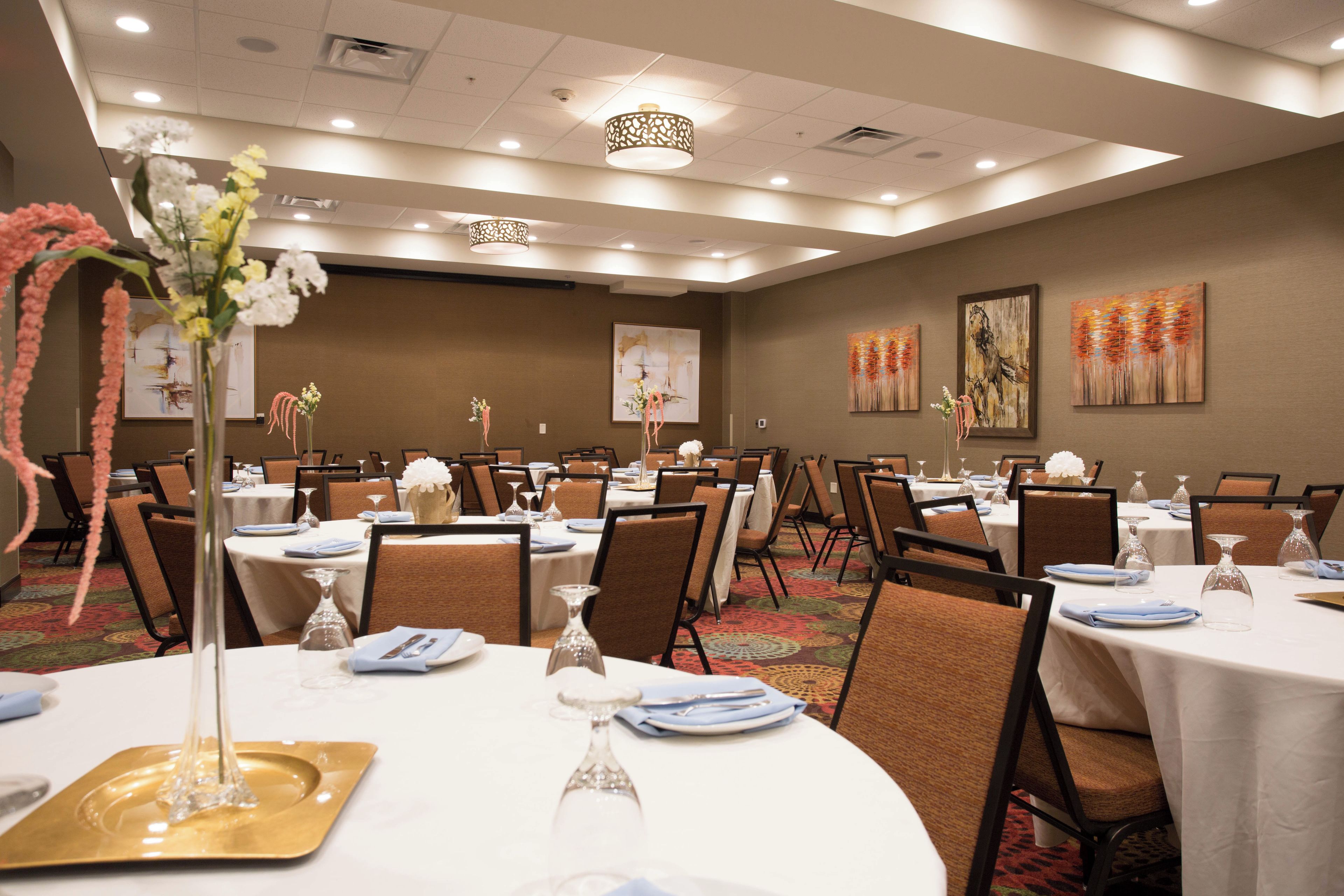 A conference room with round tables, chairs, and floral centerpieces.