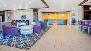 A lobby with seating areas, a reception desk, and a mural of a sunset. - La Quinta Inn & Suites by Wyndham Corpus Christi - Portland (Portland)