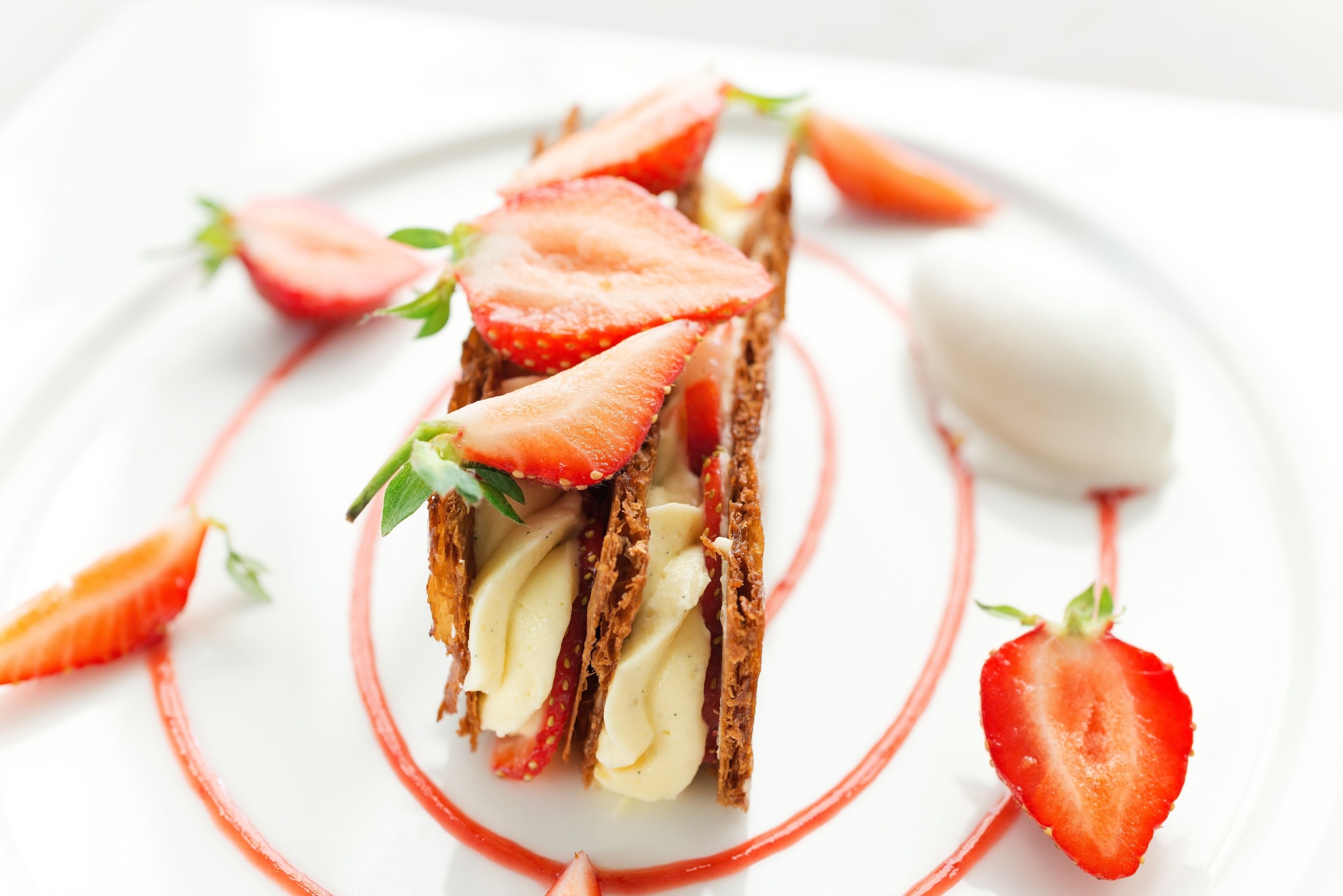 A dessert with strawberries and cream on a white plate.