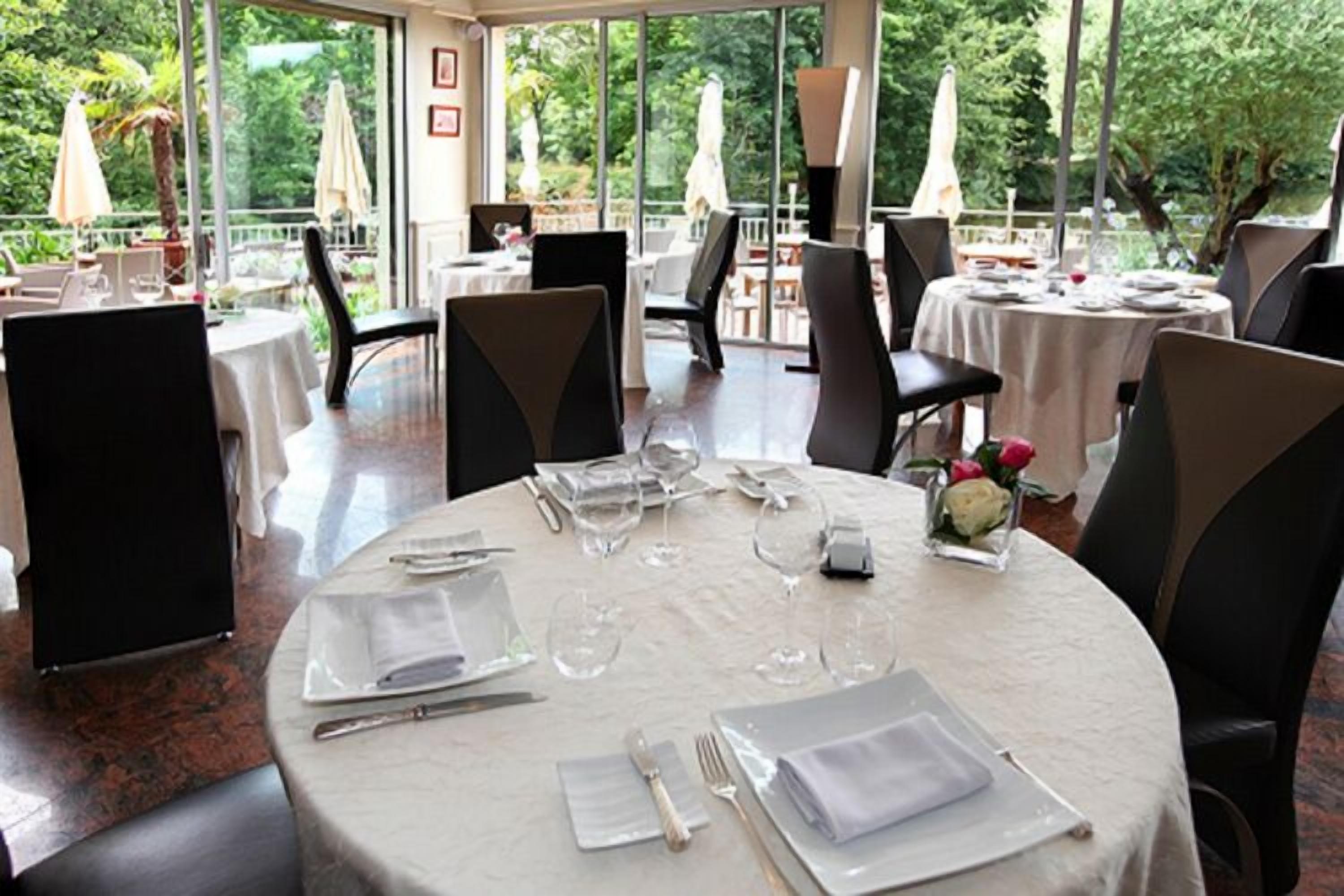 A restaurant with round tables set for dining, featuring clear glassware and white napkins.