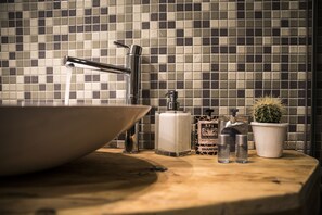 A bathroom with a large sink, a faucet, a soap dispenser, and a cactus plant. - Serendipity Rooms (Milan)